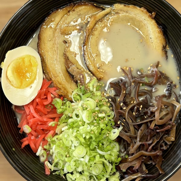 Mako Ramen bowl with pork belly, soft-boiled egg, red ginger, green onions, and wood ear mushrooms.