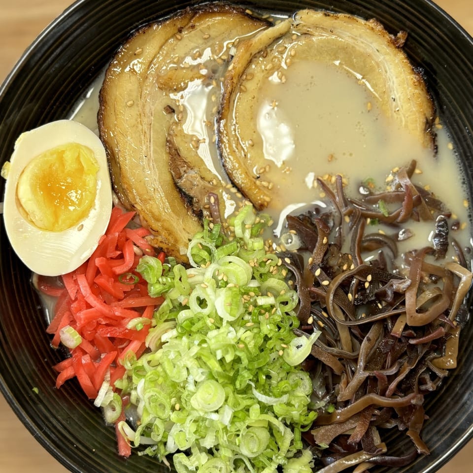 Mako Ramen bowl with pork belly, soft-boiled egg, red ginger, green onions, and wood ear mushrooms.