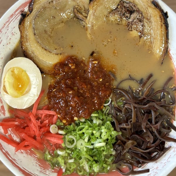 Close-up of Mako Ramen with pork belly, soft-boiled egg, chili paste, wood ear mushrooms, and scallions.