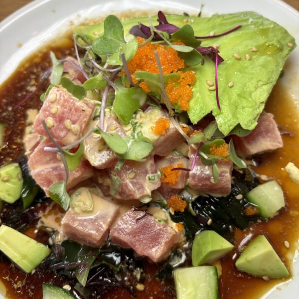 Tuna poke with avocado, microgreens, tobiko, and cucumber in a savory sauce.