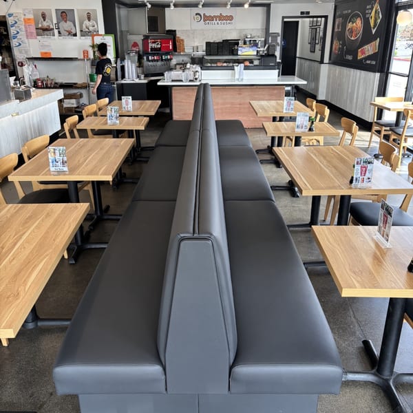 Interior of Mako Ramen restaurant with black booth seating, light wooden tables, and a counter area.