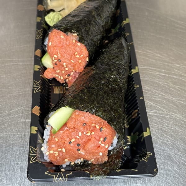 Two Mako Ramen spicy tuna hand rolls with avocado, sesame seeds, and nori, in a black tray.